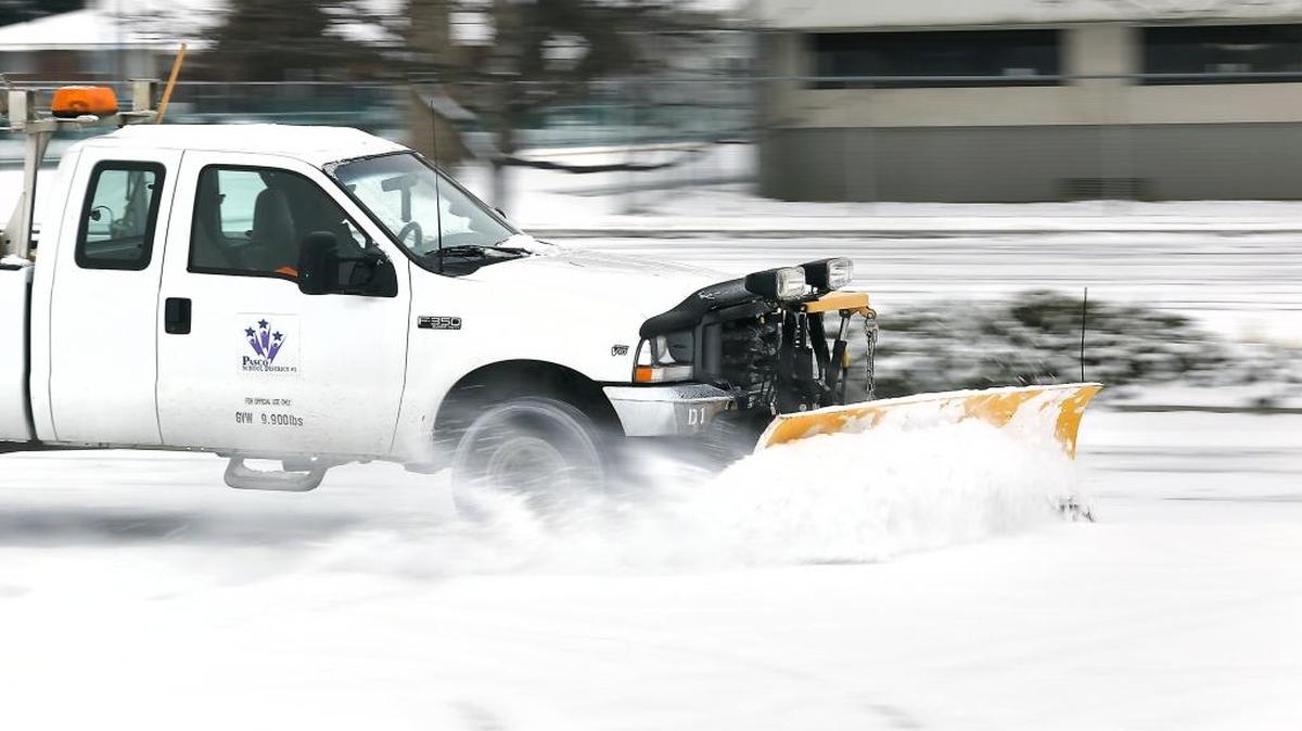 A school district employee removes recent snowfall Wednesday morning from the empty faculty parking lot at Stevens Middle School on Wednesday morning in Pasco. The Tri-City economy continues to expand while the unemployment remains near record low levels.