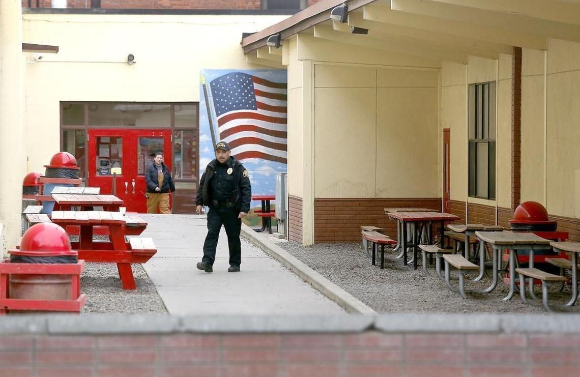 A Prosser police officer and school official search outside of Prosser High School Tuesday after a suspicious device was discovered on the campus.