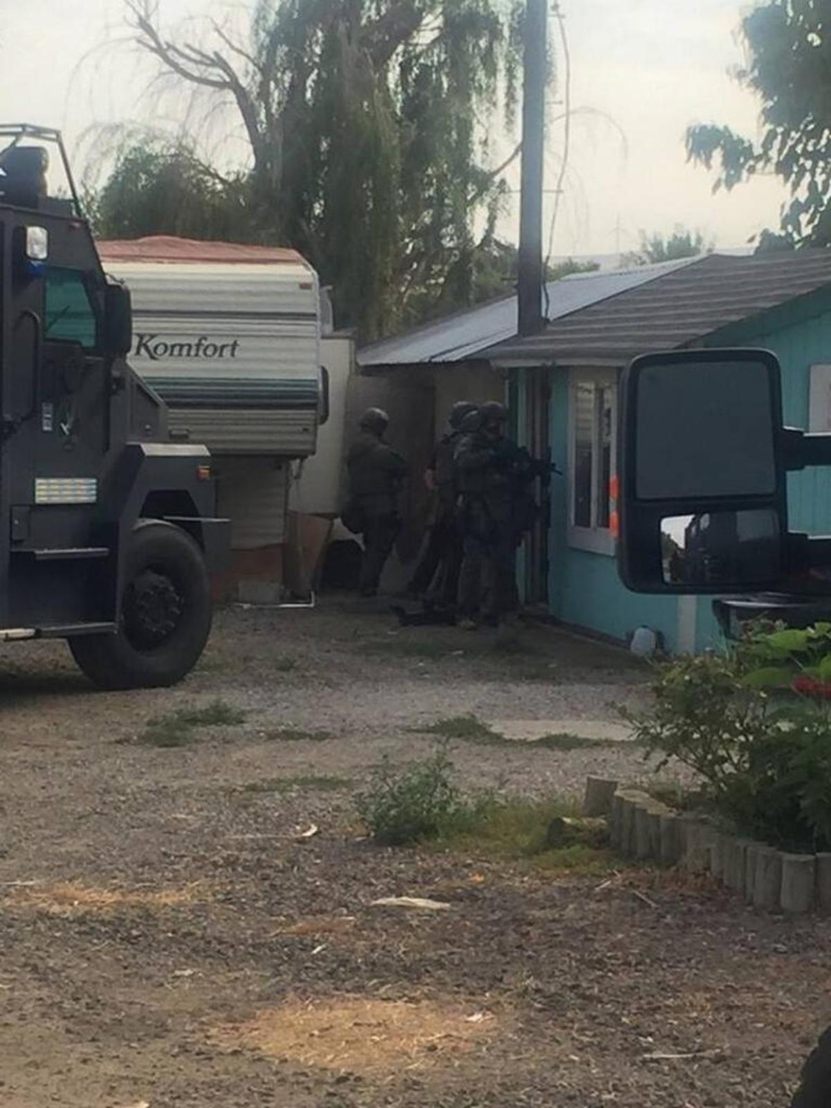 Officers line up outside a house in Finley on Thursday during drug raids there and in Pasco.