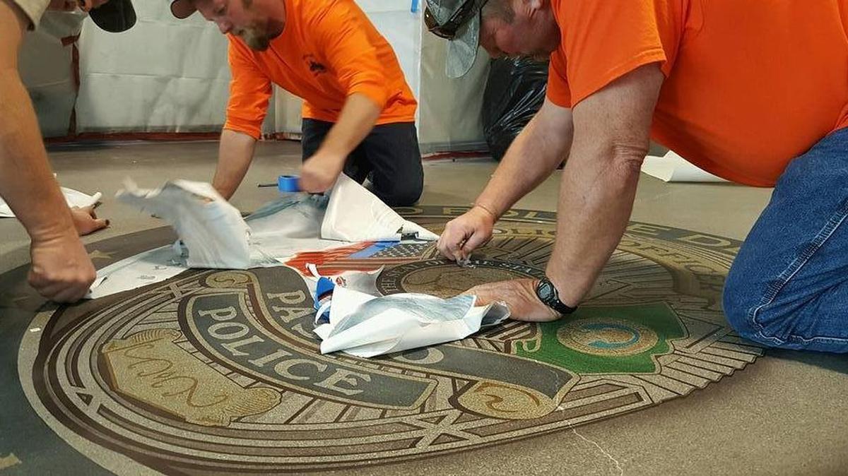 Employees with Creative Concrete Design Inc. & Floor Polishing Systems of Pasco install a vinyl stencil on the lobby floor of the new Pasco Police Community Services Building. The custom logo, which features the department’s shield, was designed by FLOORmaps Inc. of Arkansas. Kathren Knigge, FLOORmaps’ business director-owner and assistant graphic artist, took the pictures during the installation. The emblem will get a layer of sealant before the floor is polished.