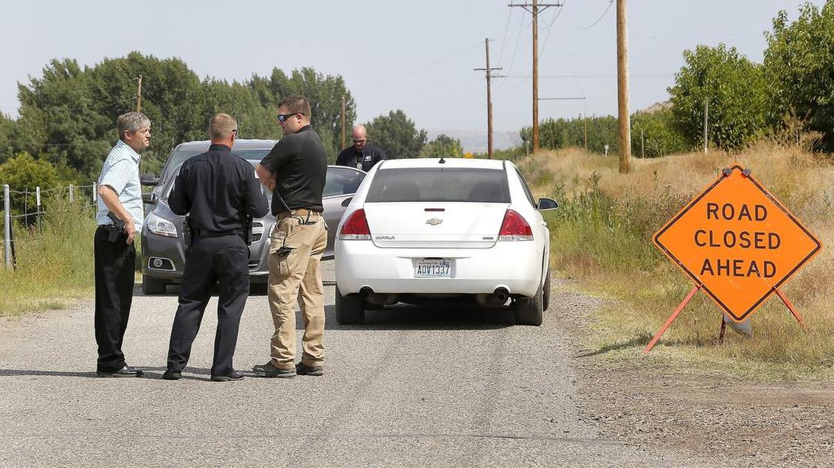 Law enforcement officials from the Pasco Police Department and Benton County Sheriff's Office stand on Columbia River Road during Friday's investigation of a decomposed body discovered along the Columbia River in rural Franklin County.