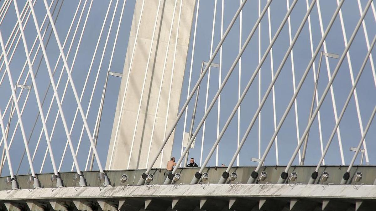 Kennewick police Sgt. Ken Lattin convinces Anthony Aguilar, 44, to climb over the railing and safely walk off the cable bridge Wednesday after he threatened to jump into the Columbia River. The incident began when officers responded to Clover Island for a disturbance between Aguilar and a woman. Aguilar ran from the officers to the bridge. Bridge traffic was sporadically disrupted for about two hours before Aguilar agreed to come down and was cited and released.