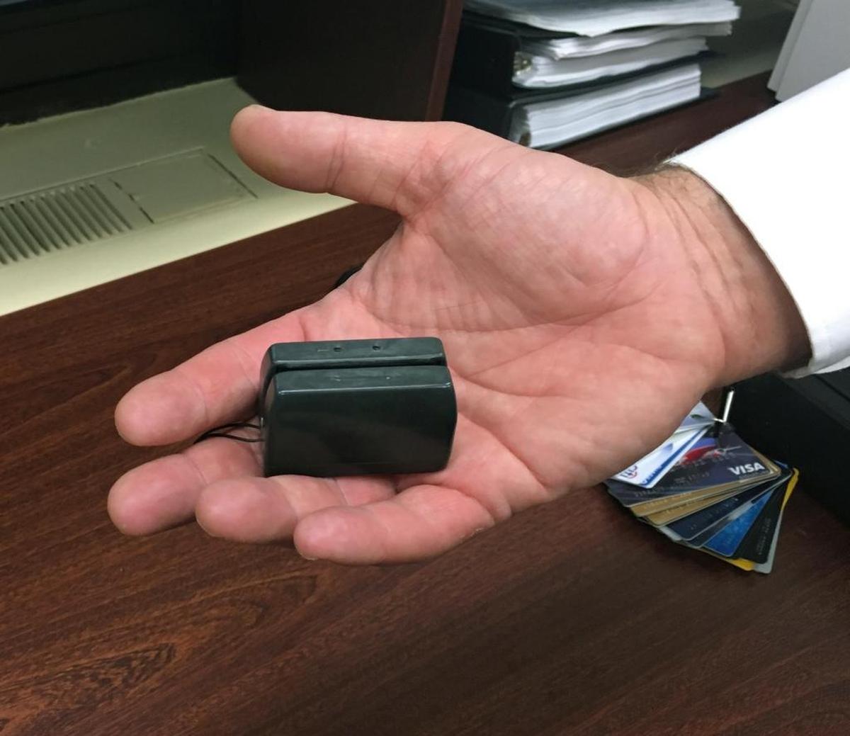 A New York City police detective holds a credit card skimmer used to copy metadata from legitimate credit cards for use in the manufacture of counterfeit cards and possibly identity theft.