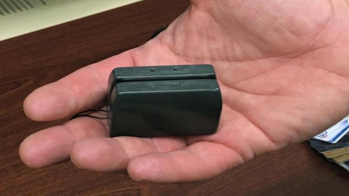 A New York City police detective holds a credit card skimmer used by a street gang to copy metadata from legitimate credit cards for use in the manufacture of counterfeit cards and possibly identity theft.