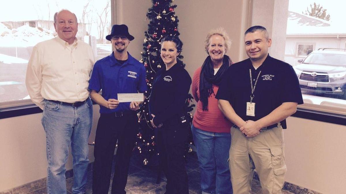Representatives from Mid-Columbia Meals on Wheels receive a donation from the Kennewick police and firefighters.