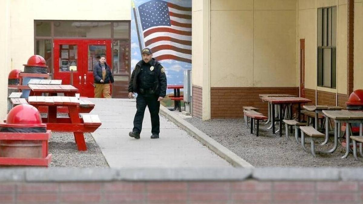 A Prosser police officer and school official search outside of Prosser High School Tuesday after a suspicious device was discovered on the campus.