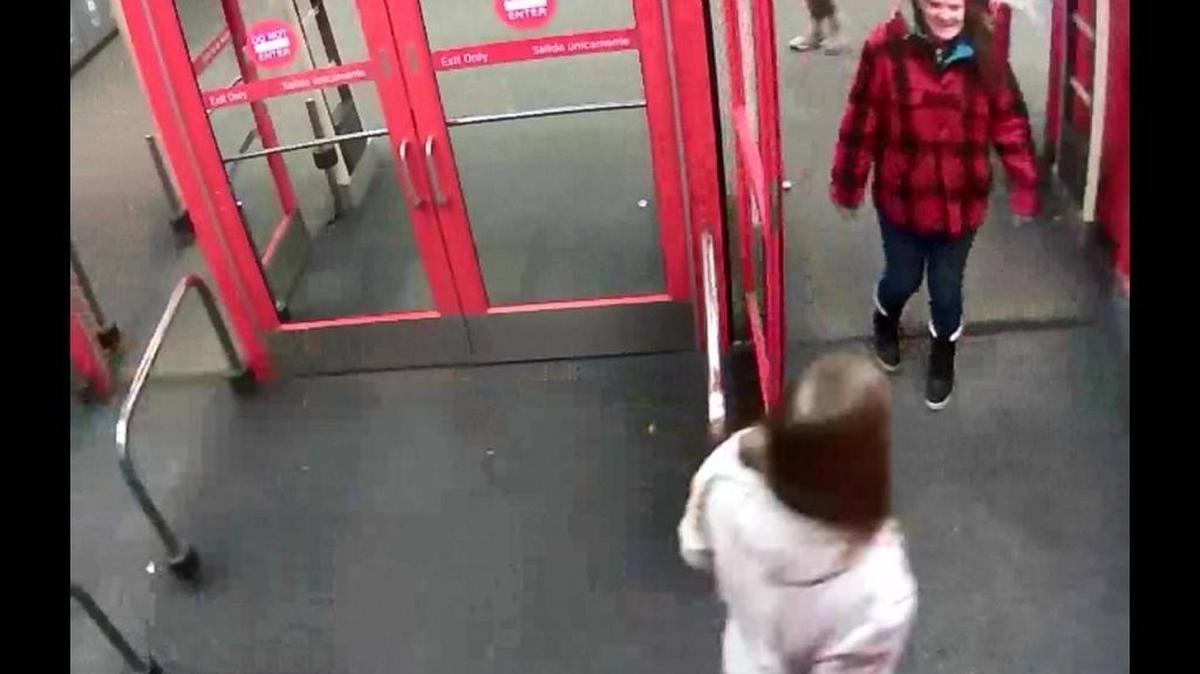Kennewick police claim the woman in the red coat is leaving the Target store without paying for her boots.
