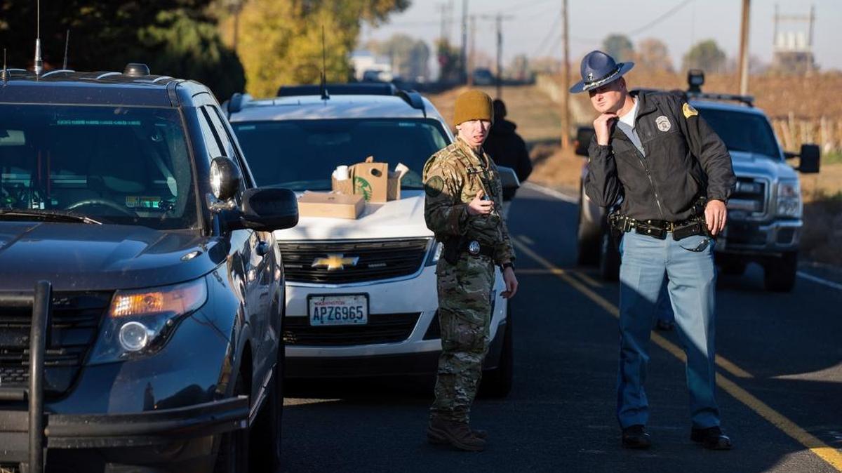 Washington State Patrol troopers and detectives investigate the scene after two suspects and a state patrol trooper exchanged gunfire near Grandview. Authorities are searching vineyards for the men they said opened fire on a trooper who tried to pull them over for speeding.