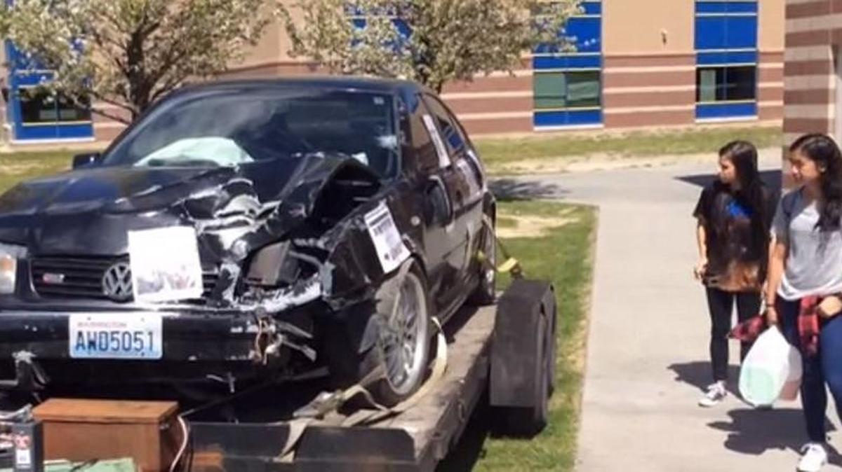 Two Southridge High School students look at a car damaged in a collision caused by distracted driving during an event in the spring. The state is requiring people to put down their phones while driving.