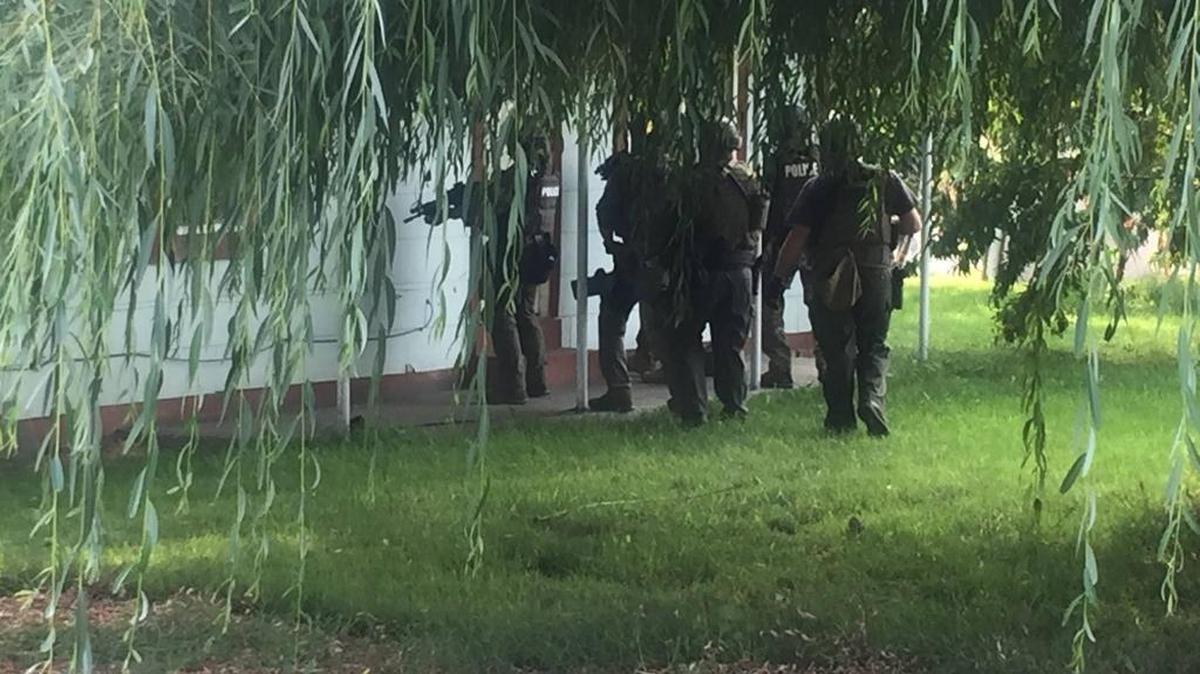 Officers line up outside the door of a house Thursday during raids in Finley and Pasco.