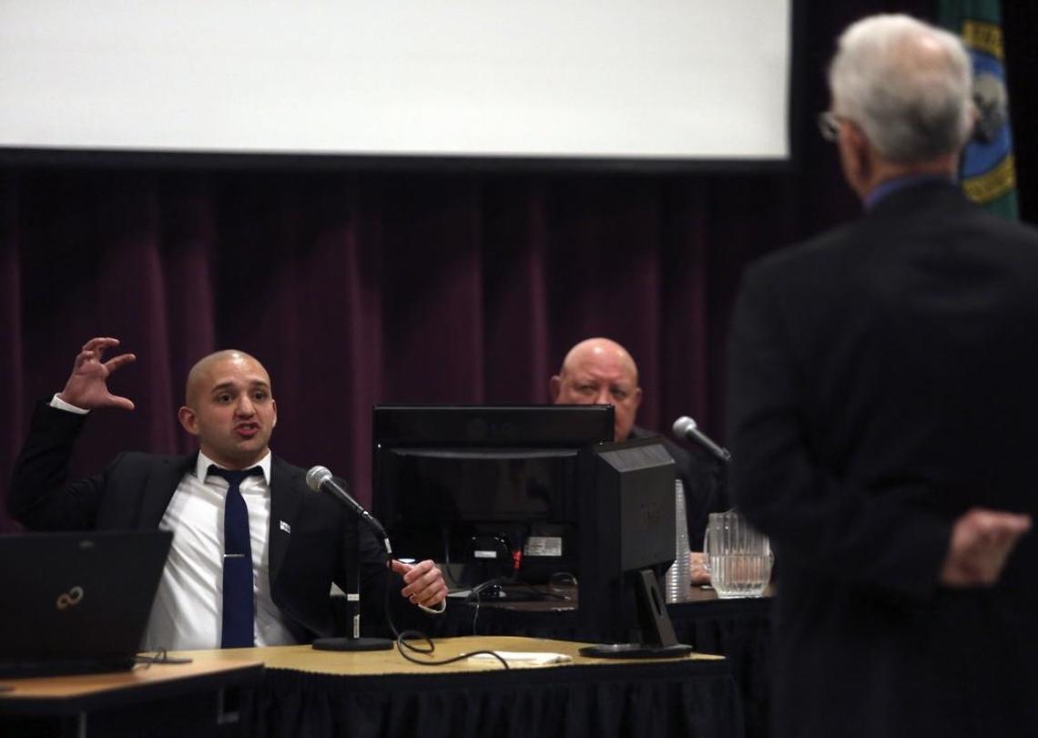Pasco police Officer Adrian Alaniz demonstrates for jurors in the Franklin County coroner’s inquest how rocks were being thrown by Antonio Zambrano-Montes before the fatal shooting in February 2015. Franklin County Coroner Dan Blasdel, right, looks on.