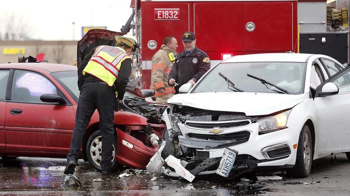 Fire and police officials investigate the cars involved in Friday afternoon’s crash at the intersection of Highway 395 and West Kennewick Avenue in Kennewick. Both drivers were hurt.