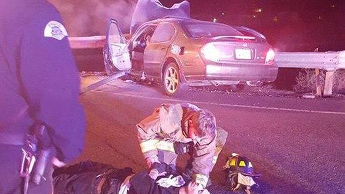 A firefighter attends to a man pulled from a car that caught fire after hitting a light pole Thursday afternoon in Pasco.