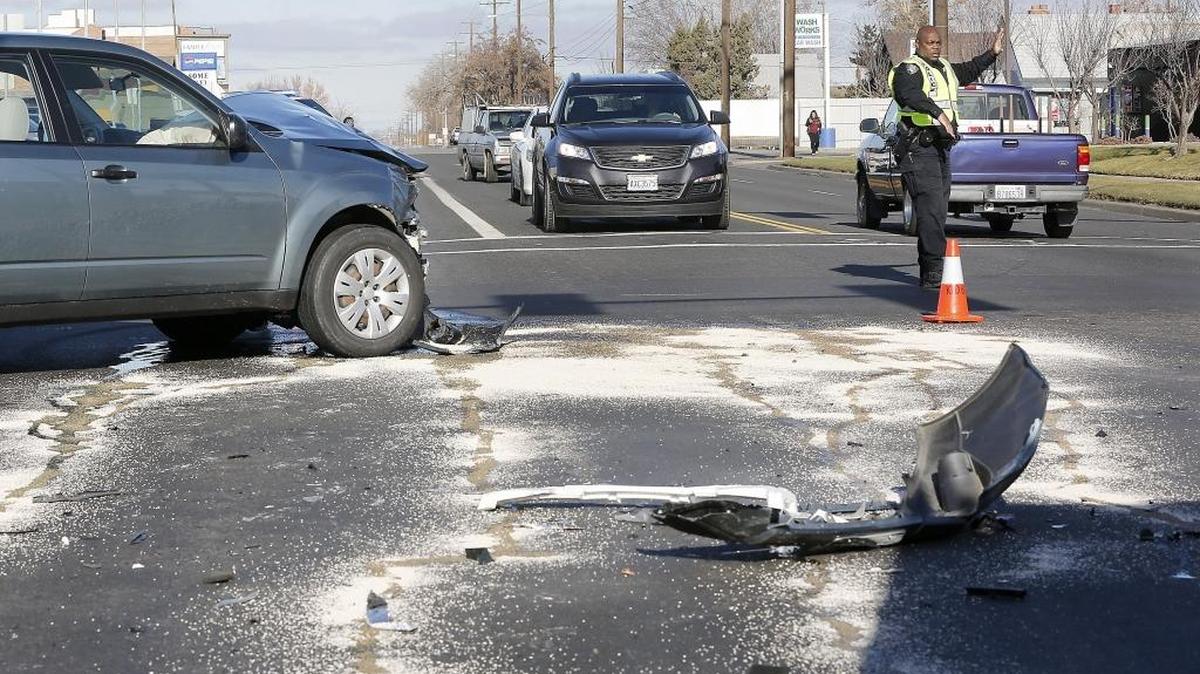 Kennewick police Officer James Canada directs traffic Monday around a two-car collision at the intersection of West 10th Avenue and South Washington Street in Kennewick. Witnesses told police the Subaru Forester, headed east on West 10th, failed to stop for a red light and collided with a southbound Chevrolet sedan. Two people were taken to the hospital with non-life threatening injuries, according to Kennewick fire officials. The wreck caused delays for motorists until tow trucks could remove the damaged vehicles.
