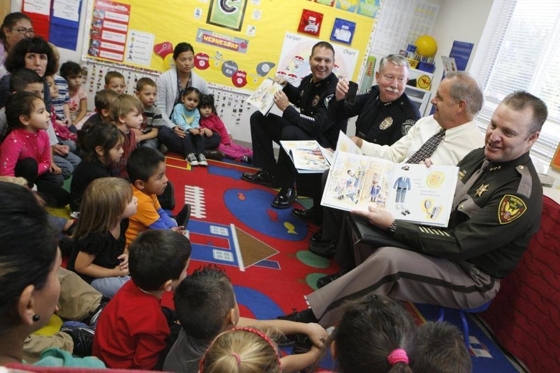 Chief Ken Hohenberg shows Benton County Prosecutor Andy Miller the modern version of a police radio in this file photo as they joined Benton County Sheriff Steve Keane, right, and Richland Police Chief Chris Skinner in reading Police Officers on Patrol, written by Kersten Hamilton, to Head Start classes in 2012.