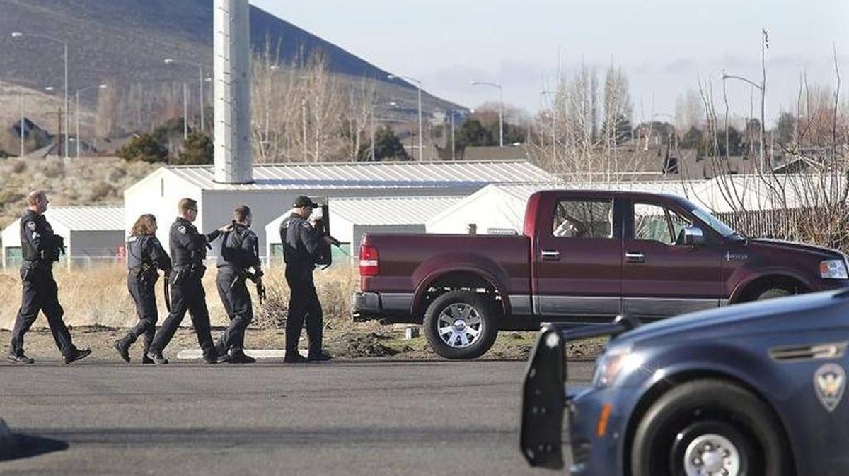 Richland police officers cautiously approach a Lincoln pickup Tuesday afternoon, making sure a male gunshot victim sitting in the backseat can’t get a weapon while parked near the gas station on the corner of Queensgate Drive and Keene Road.