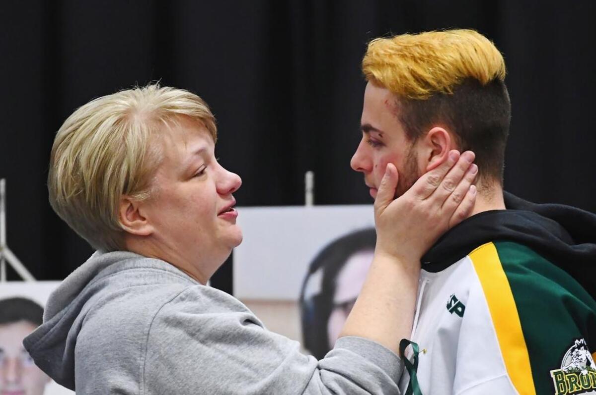 Humboldt Bronco Nick Shumlanski, who was released from hospital Sunday, is comforted by a mourner during a vigil at the Elgar Petersen Arena, home of the Humboldt Broncos.