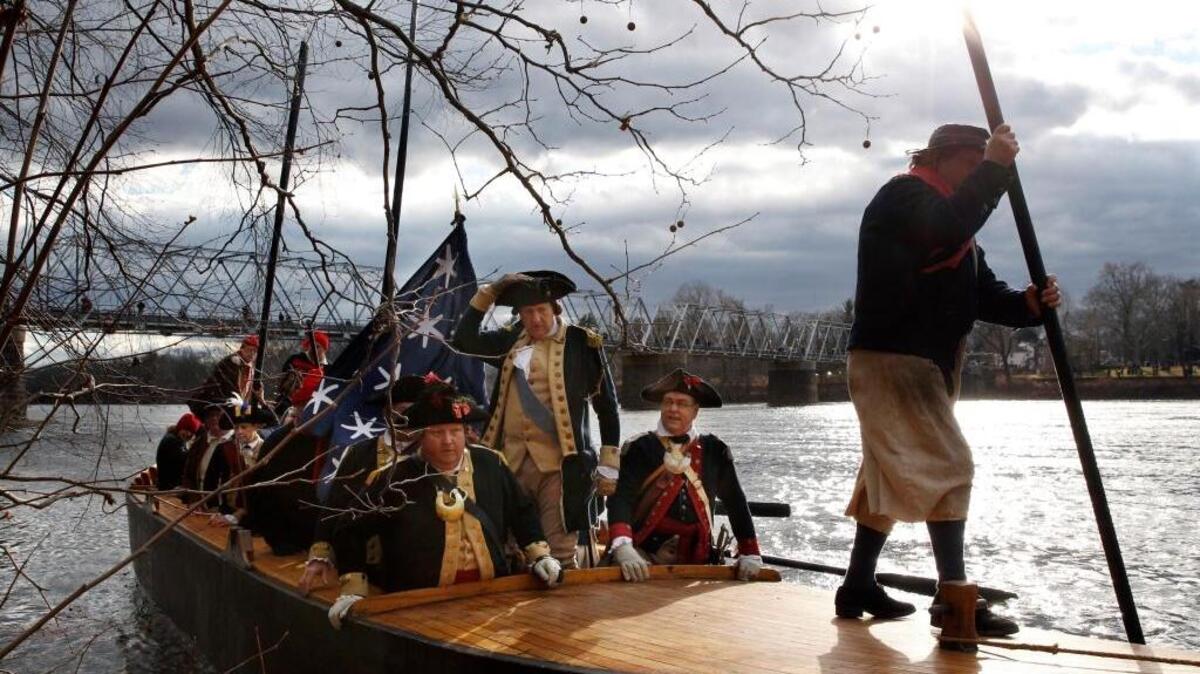 George Washington, played by John Godzieba, standing center, holds onto his hat as he and his troops land in Titusville, N.J., after crossing the Delaware River during the 62nd annual reenactment of Washington’s daring Christmas 1776 crossing of the river in Washington Crossing, Pa. in 2014. The historic crossing turned the tide of the Revolutionary War.