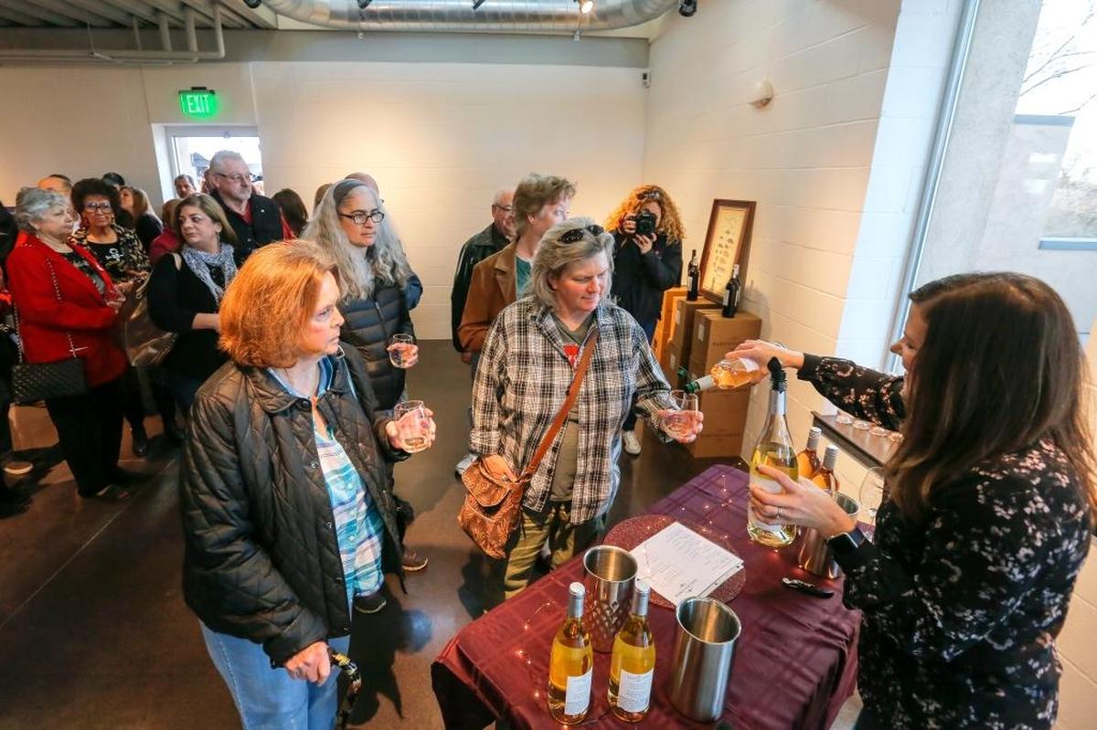 Carolyn Raymond, left, waits as her daughter Shannon Tisdel, center, gets a sample of Bartholomew wine from Jo Bader, right, inside of Bartholomew Winery on Friday after the Port of Kennewick held its ribbon cutting for Columbia Gardens Urban Wine & Artisan Village.