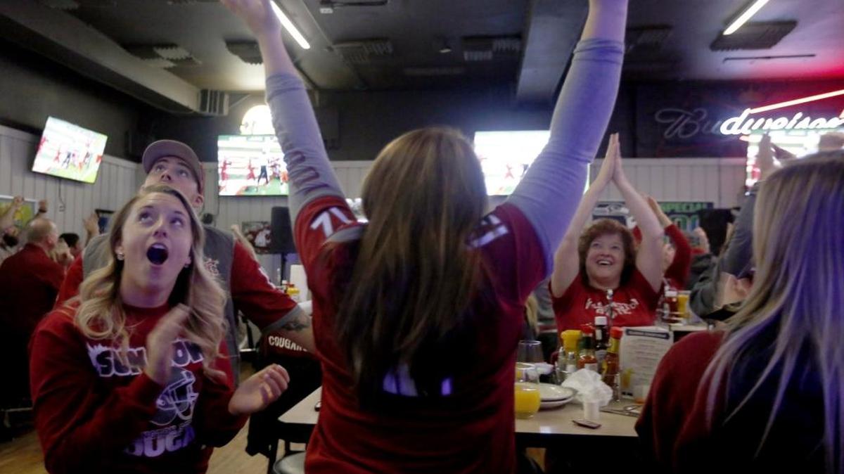 Washington State alumni Taylor Neubauer, left, cheers along with friends Bailey Smith, right, and Adam Jones on Saturday at the Gaslight Bar & Grill in Richland while watching the WSU football team play the University of Miami in the Sun Bowl in El Paso, Texas.
