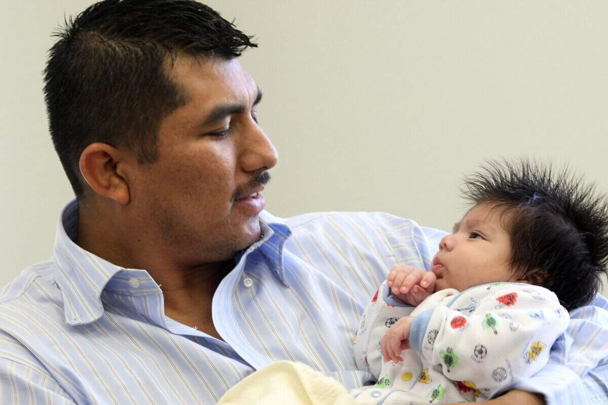 2008 FILE PHOTO: Juan Campos Gomez cradles his infant son, Salvador, during an interview.