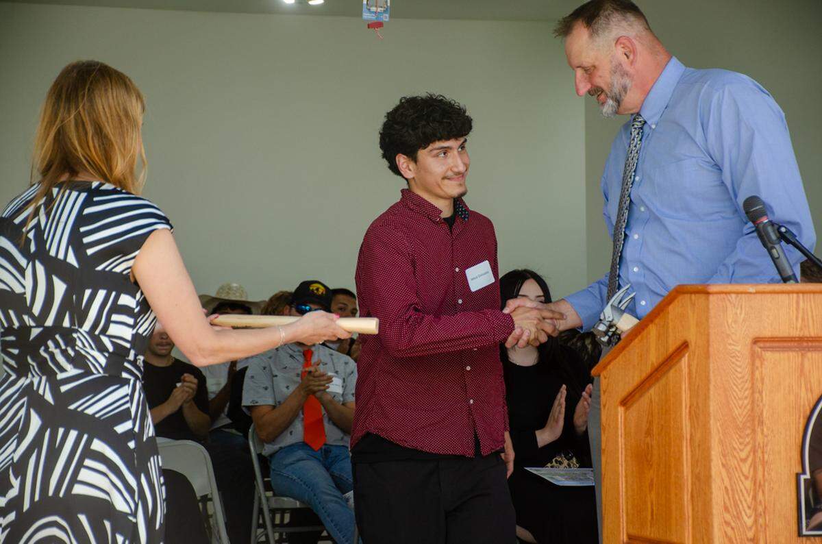 Pasco High School student Jesus Gonzalez receives a Golden Hammer award on Thursday during the dedication ceremony for Team Pasco’s 26th house built by students and instructors. He’s pictured here with Pasco School District CTE Director Laura Jones and instructor Chris Lambert.