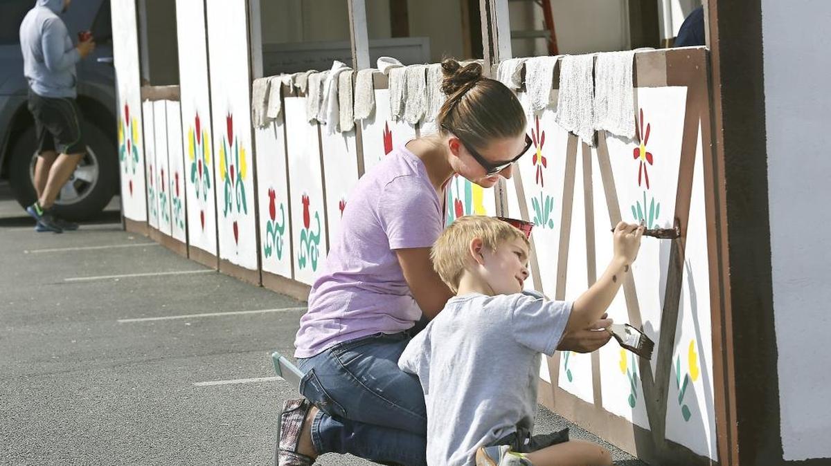 Remmington Alford, 4, concentrates Wednesday on staying inside the lines while helping his mom, Morgan, touch up the painted borders on food booths for the annual Sausage Fest at Christ The King Catholic School in Richland.