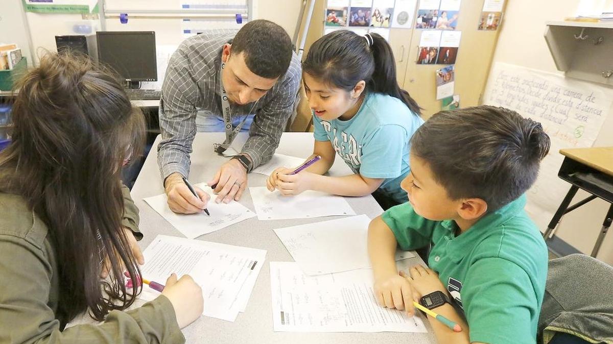 Bilingual teacher Severo Rodriguez helps fifth-grade students with a math assignment Monday in his classroom at Maya Angelou Elementary School in Pasco. From left, are Kianna Mendoza Montoya, Michelle Morales and Jesus Peña. The Senate and House have dueling proposals both aimed at increasing the number of bilingual teachers.