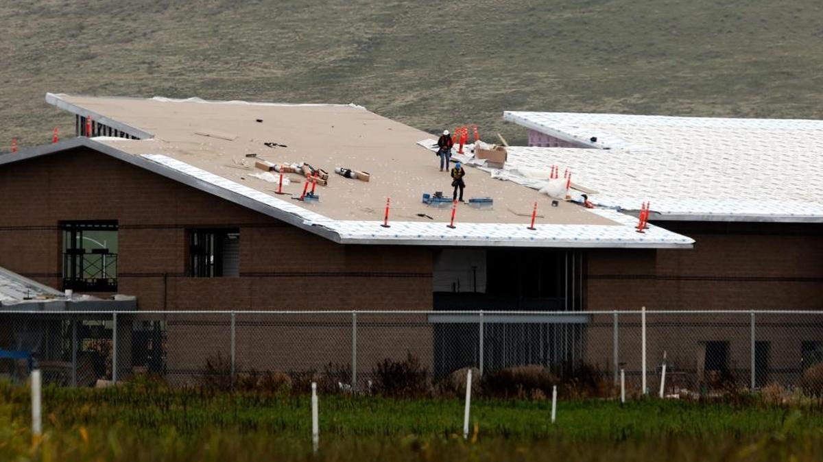 Construction personnel work Tuesday on the roof of the new Richland School District middle school under construction near the intersection of Keene Road and Belmont Boulevard in West Richland. The farm property in the foreground is part of the 70 acres of land the school district is in the process of purchasing for a new high school.