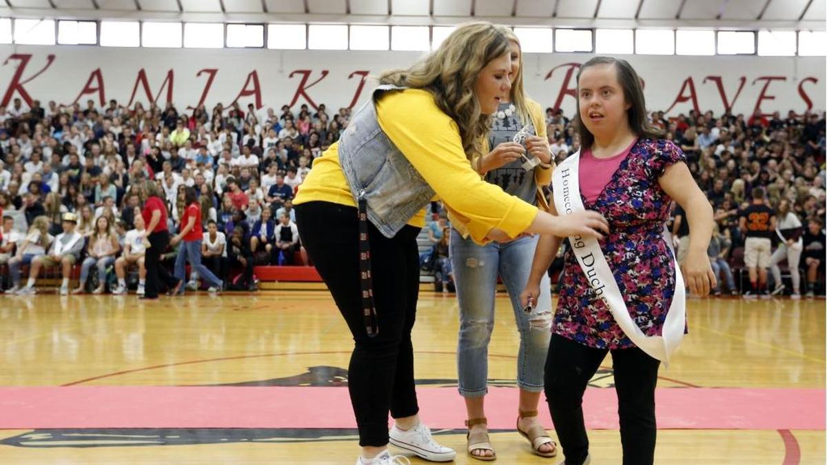 
Jamie Jimenez, a LifeSkills student, puts on her Homecoming Duchess sash Friday with help from juniors Emily Rosenblum, left, and Madeline Lindholm, center, during a homecoming assembly at Kamiakin High School. 
