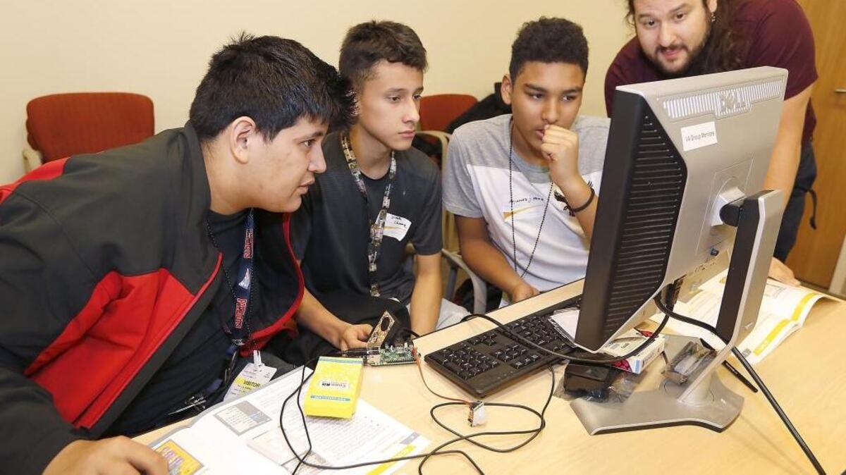 Chiawana High students Lucio Rodriguez, Joseph Chavez and Alejandro Perez, from left, work with Jeremy Zucker, a computation biologist at PNNL, Tuesday while programming a Raspberry Pi equipped with sensors to detect motion during a PNNL Computer Day event. About 70 students from the Pasco school attended with their STEM teachers as part of Computer Science Education Week. Watch a video at tricityherald.com/video