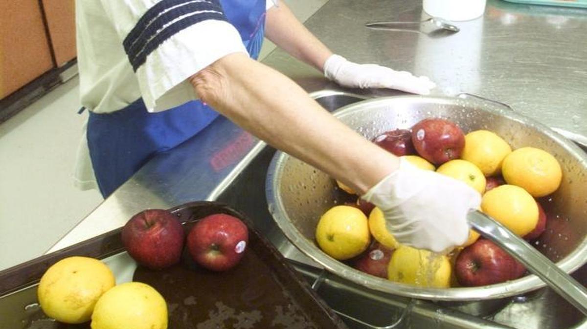 A food service worker washes off fruit at the Hanford High School cafeteria in this file photo.