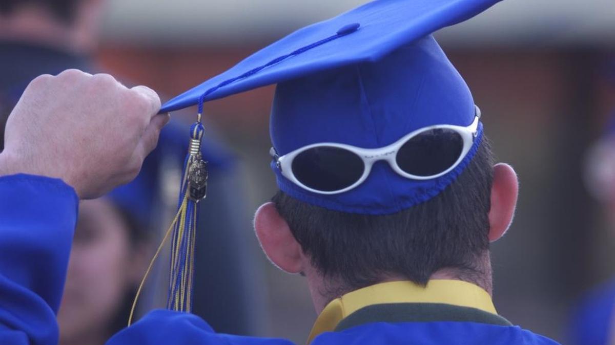 A graduate adjusts his mortarboard.