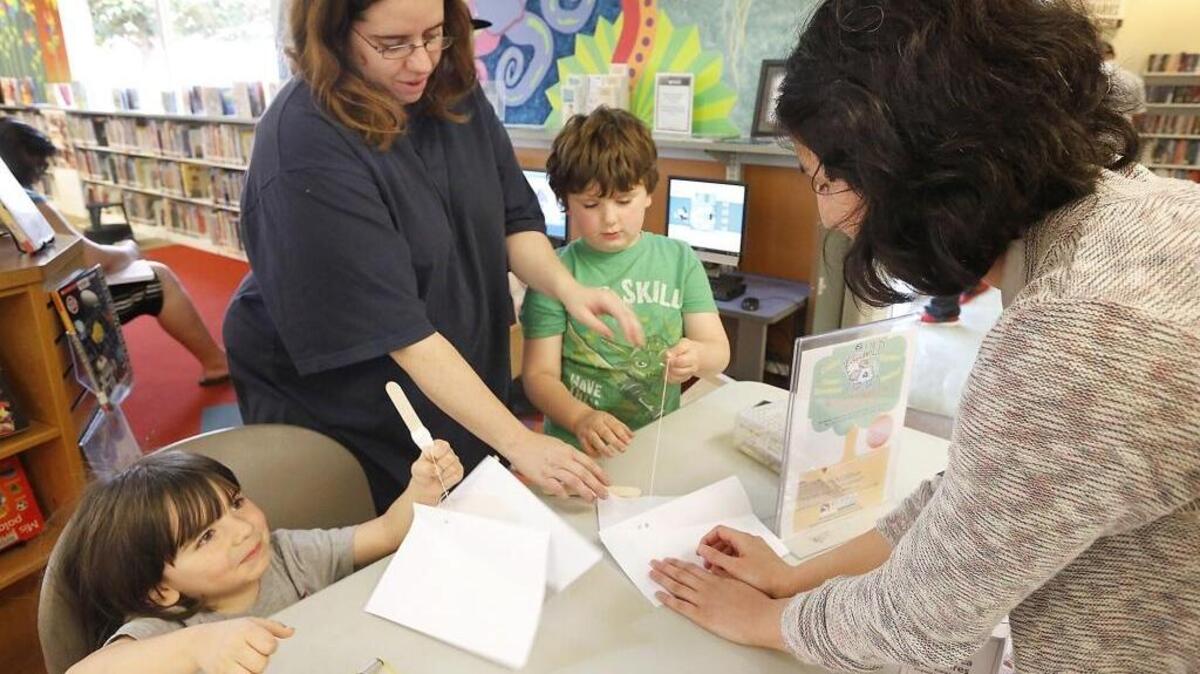 Tiffany Soto of Kennewick and her sons Adrian, 4, left, and Damien, 5, are helped in 2015 by Monica Linares, a member of the Regional Service Corps - AmeriCorps, making paper kites at the Keewaydin library in Kennewick.