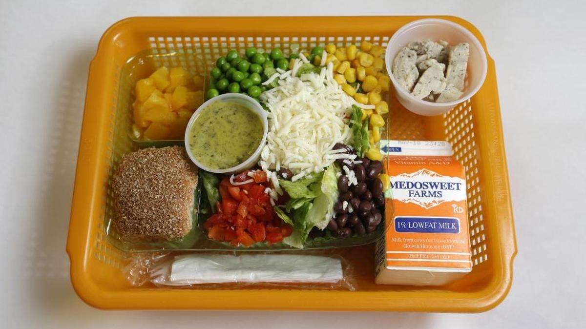 A school lunch salad entree option featuring low-sodium chicken, a whole-grain roll, fresh red peppers, and cilantro dressing at Mirror Lake Elementary School in Federal Way, Wash