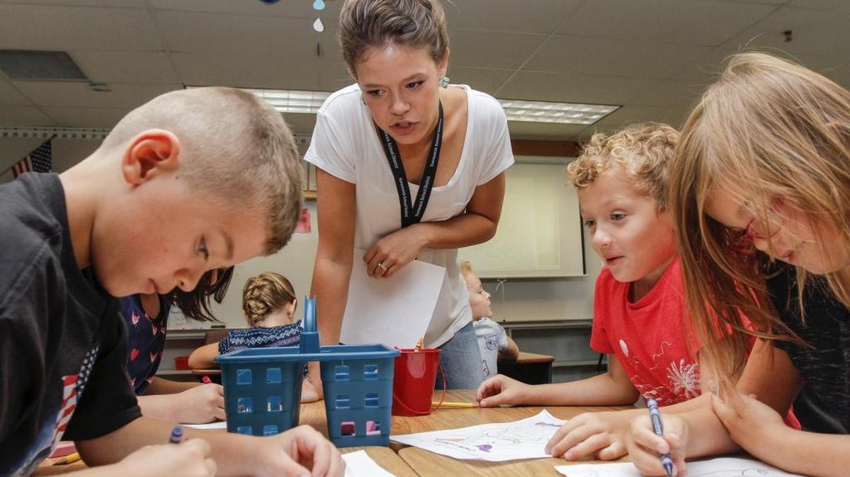 Emily Steltenpohl, center, a second grade teacher, talks to her students as they color on Tuesday during the first day of school at Hawthorne Elementary in Kennewick. The 22-year-old teacher is one of 91 new teachers in the district starting classes today.