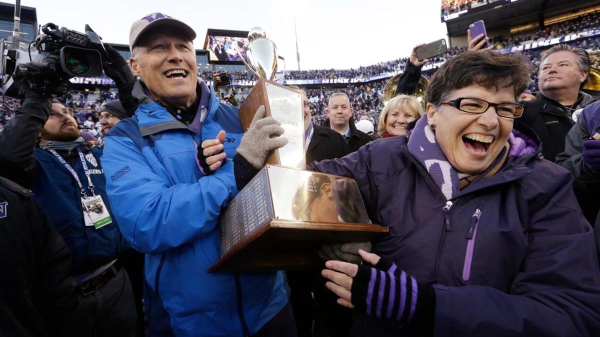 Gov. Jay Inslee, left, holds the Apple Cup Trophy with Washington president Ana Mari Cauce after Washington beat Washington State in 2015 in Seattle.
