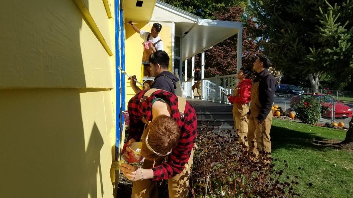 Students from Tony Milewski’s construction trades class Wednesday paint Doug and Loree Swartz’s home on Irby Street.