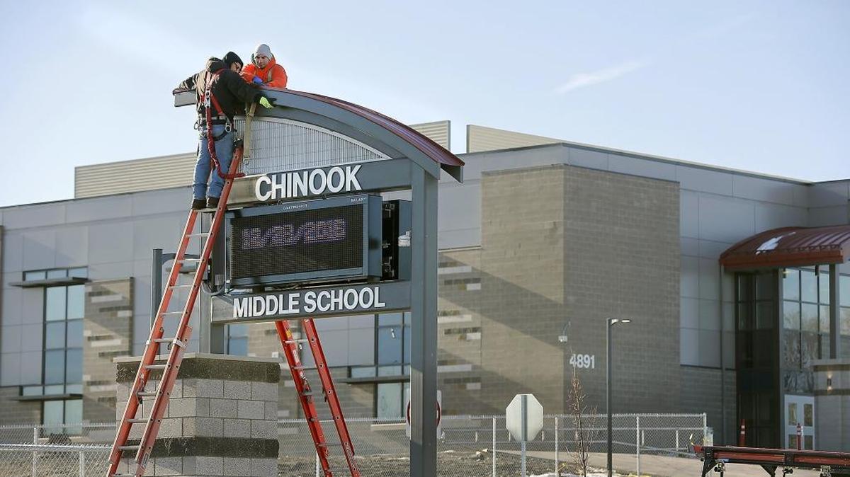 Angel Cuevas, left, and his brother, Julio, both Leslie & Co. employees, work together Wednesday to install pieces of a readerboard sign at the new Chinook Middle School building in Kennewick.