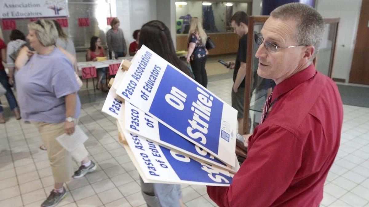 
Greg Olson, president of the Pasco Association of Educators, carries a handful of strike signs for display at Monday night’s union membership meeting at Pasco High School.
