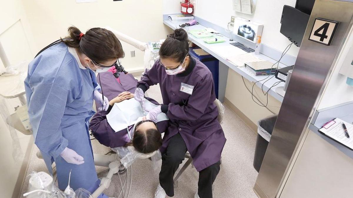 CBC dental hygiene student Lauren Silver practices giving a shot of Novocaine to classmate Nelya Sirotinskiy under supervision from instructor Robin Roderick.