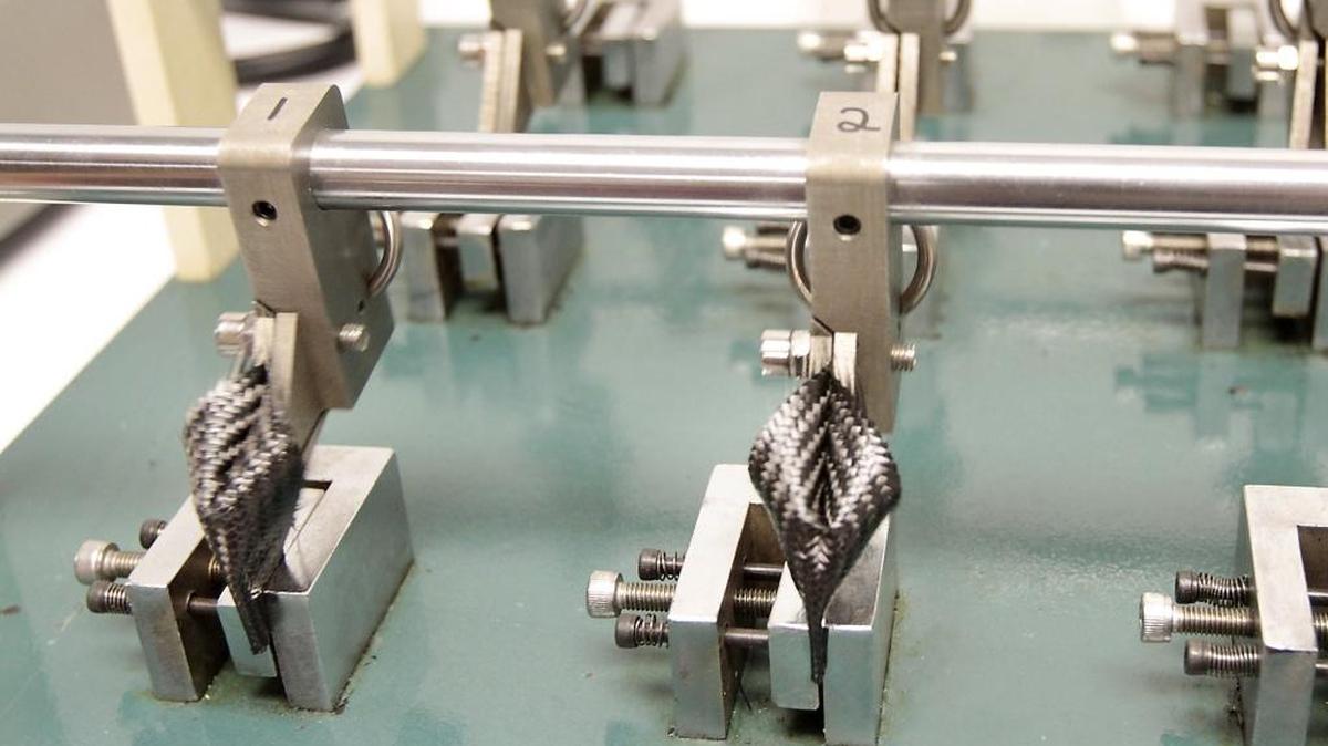 Strips of soft carbon fiber material are tested for durability in a flex testing machine at Carbitex in Kennewick.