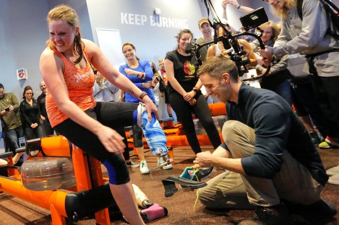Cassi Juell, left, smiles and looks over to her husband as Kasey Johnson, right, of Columbia Basin Prosthetics & Orthotics, helps Juell with her new custom prosthetic leg inside of OrangeTheory in Richland on Saturday.