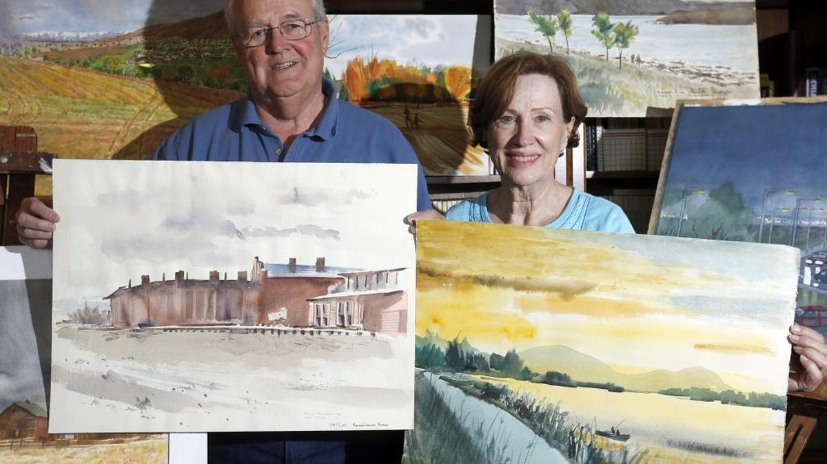 Olga Cadish, daughter of late artist Roy Brooks Pettus, and family friend Terry Mauer stand with some of Pettus’ depictions of Tri-City scenes at his home in Kennewick. Hundreds of his paintings are among the items in an estate sale running Aug. 4-6.
