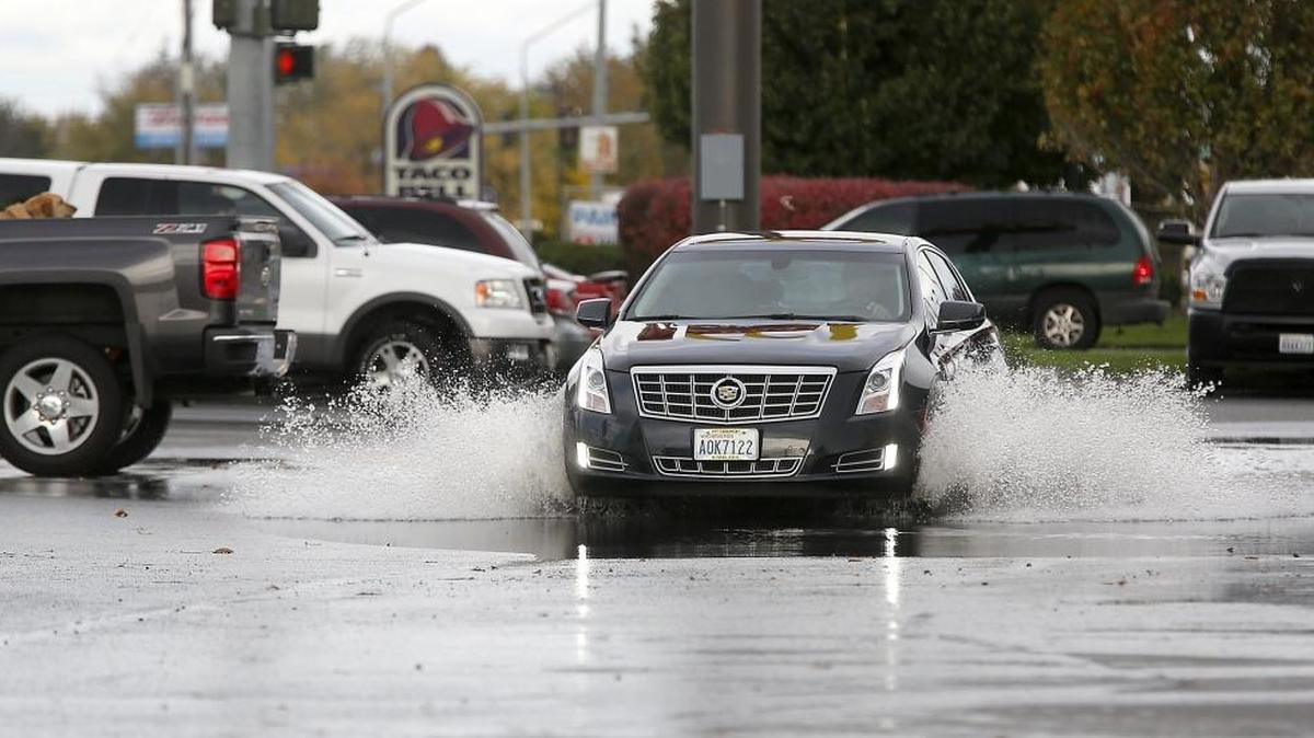 A motorist kicks up a wake Monday morning while splashing through a large puddle leftover from a Sunday night downpour in a fast food restaurant parking lot in Kennewick. Tri-Citians are likely to get a reprieve from the recent soggy weather with forecasters predicting partly sunny and partly cloudy skies over the several days.