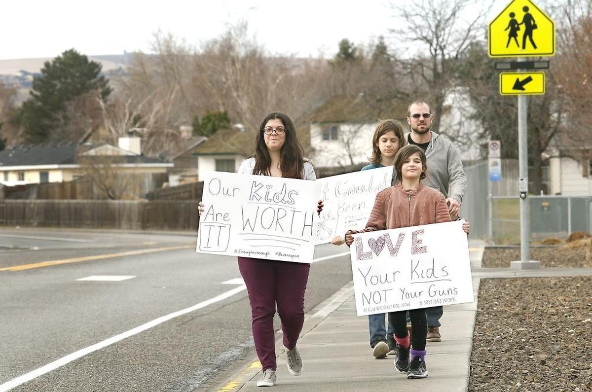 Melissa Parkes, left, is joined by her 13-year-old home-schooled son, Will, third-grade daughter, Lily and husband, Alan, for a 17-minute walkout Wednesday in front of Sunset View Elementary School. The family wanted to show support for school safety in front of their daughter’s school in Kennewick.