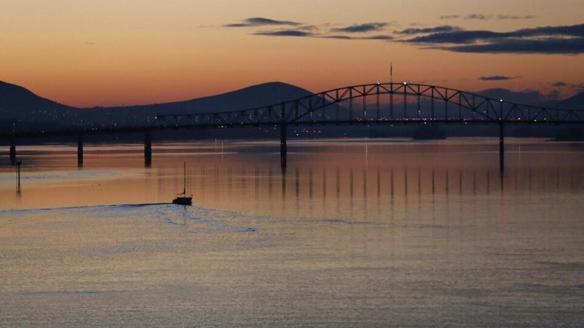 A colorful sunset reflects off the calm waters of the Columbia River Monday evening as a sailboat motors upriver towards the blue bridge.