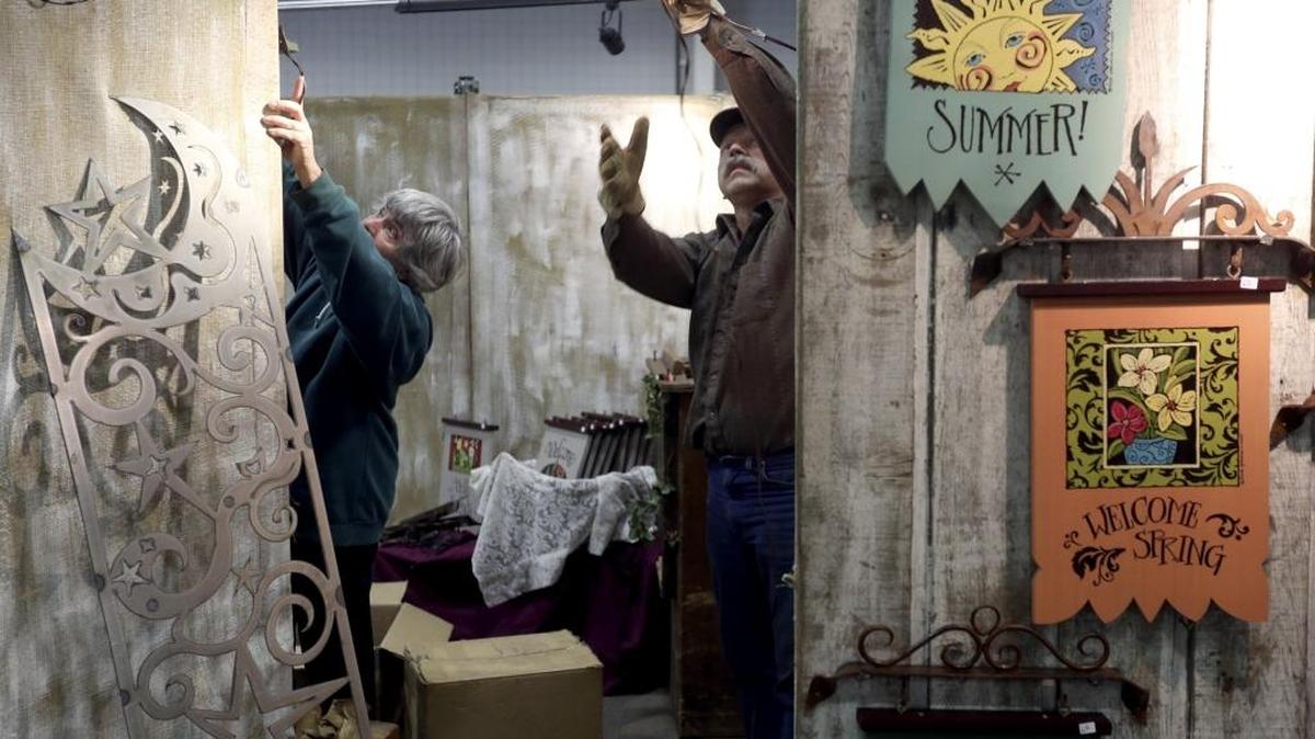 Karen Grenzow, with Cascade Designs of Sumas, hangs one of her painted garden signs as her husband Bob puts up a light Thursday while preparing for Custer's Arts & Crafts Show at the TRAC center in Pasco. The 17th annual show features 150 artisans and runs 10 a.m. to 8 p.m. March 18, 10 a.m. to 6 p.m. March 19 and 10 a.m. to 4 p.m. March 20. Cost is $6 for adults and free for kids 12 and under.