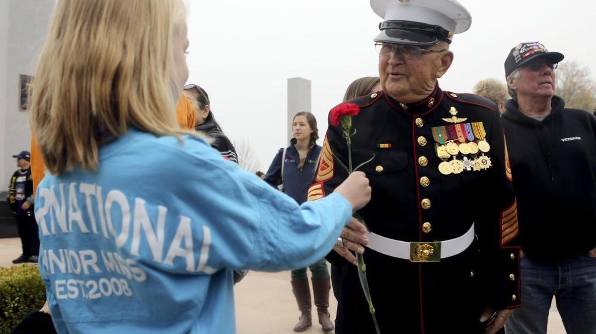 Kendall Beasley, 6, of Kennewick, hands a flower to Marine Corps veteran David Hare of Burbank during the Veterans Memorial Observance on Friday at Columbia Park in Kennewick. See a video at tricityherald.com/video