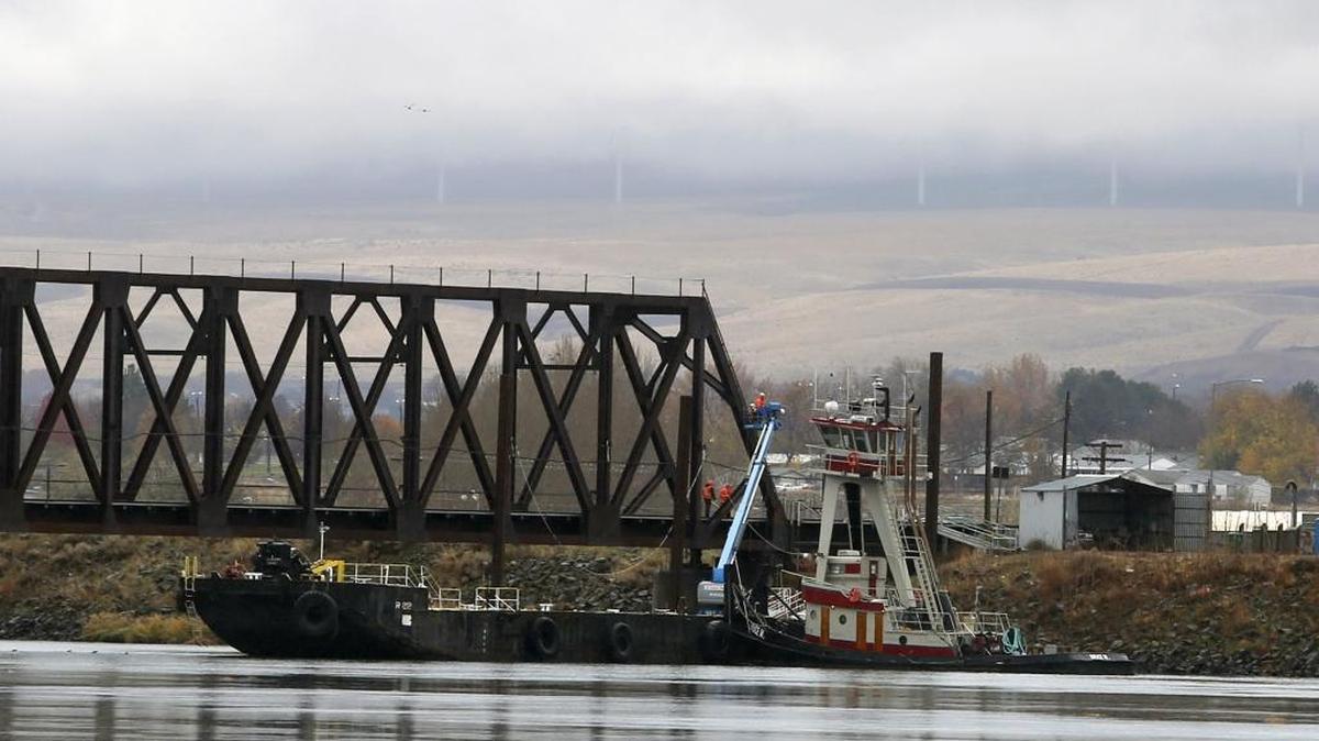 Workers on a tug and barge use a boom lift Thursday to upgrade the electrical system on the BNSF bridge over the Columbia River in Kennewick. The upgrades are part of the $550 million the railway has spent on rail system improvements in Washington state, said BNSF spokesman Gus Melonas.